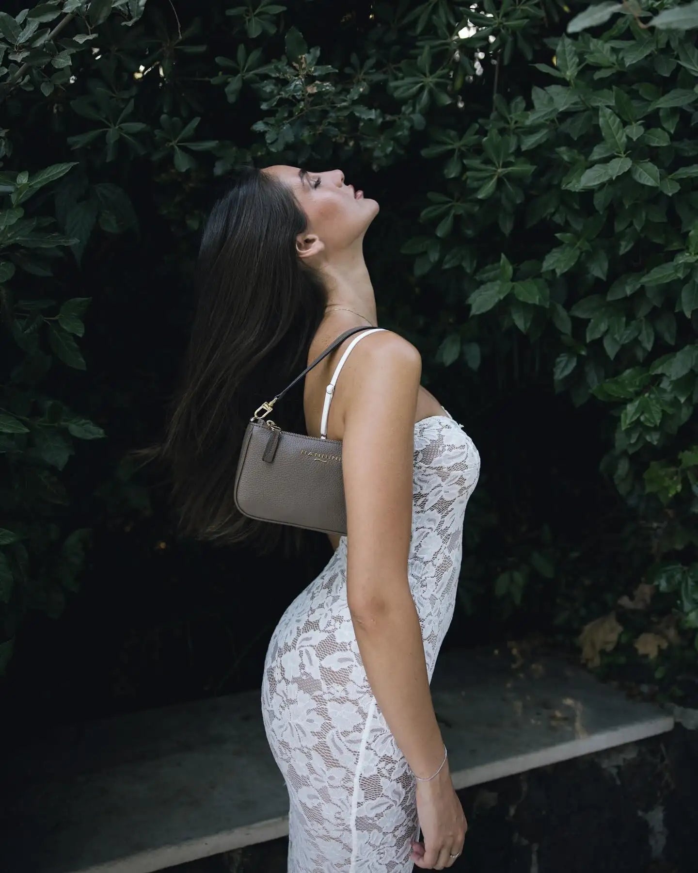 Una borsa a tracolla in pelle color taupe elegante con un design minimalista e tracolla bianca.